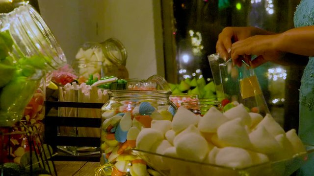 Woman filling a bag on a sweets table with bright sweet love sign 2