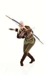 full length portrait of a blonde girl wearing green and brown medieval costume, holding a bow and...