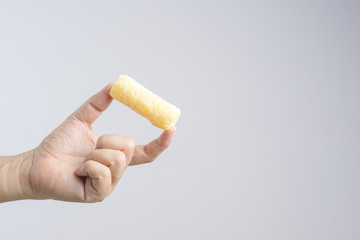 Hand holding yellow crunchy snack made from sweet corn