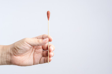 Hand holding Povidone iodine swab made of wooden stick and cotton wool for first aid