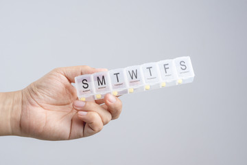 Hand holding plastic weekly pill or medicine box with Braille, the Language of the blind