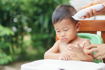 A year and sixth months old Asian baby got hair cut by his mother