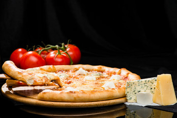 selective focus on sliced piece of appetizing Italian cheese pizza with mozzarella, gorgonzola, emmental and parmesan cheese on dark background