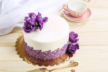 Beautiful home wedding cake decorated with purple peonies in a rustic style on wooden background.