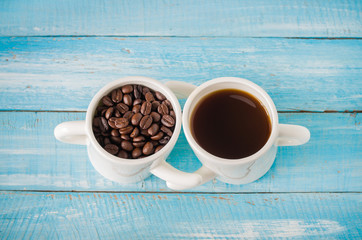 Two cup of hot coffee and roast seeds coffee  on wooden background.