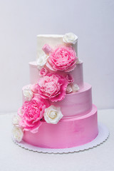 Obraz na płótnie Canvas A beautiful home wedding four-tiered cake decorated with pink roses and leaves in a rustic style