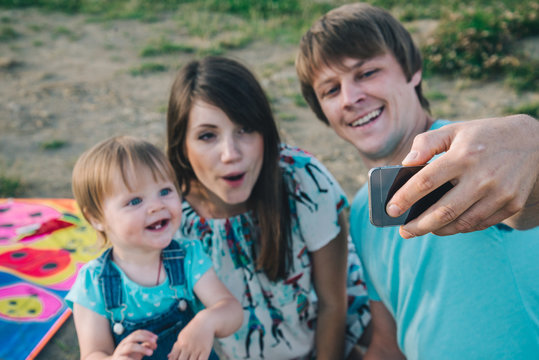 happy young family taking selfie while playing with kite