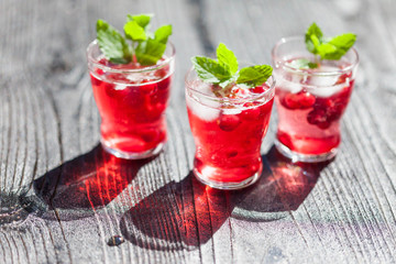 Cranberry drinks with mint on dark rustic wooden background, selective focus
