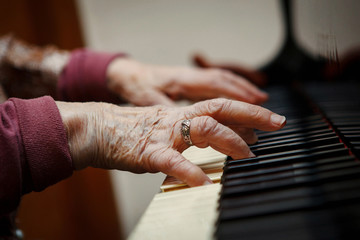 Old woman close up of hands playing the piano