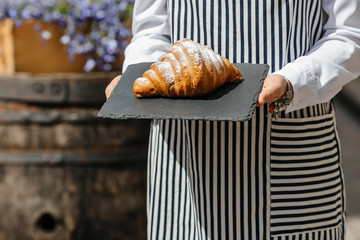 Smiling female baker showing basket with croissants