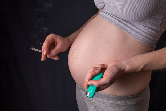 Pregnant woman with belly holding a cigarette in hands. Concept of Smoking and bad habits during pregnancy