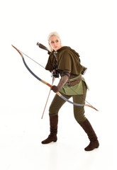 full length portrait of a blonde girl wearing green and brown medieval costume, holding a bow and arrow. isolated on white background.
