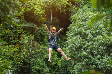 Naklejka na ściany i meble Freedom Man Tourist Wearing Casual Clothing On Zip Line Or Canopy Experience In Laos Rainforest, Asia