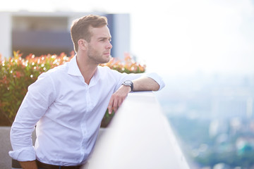 Confident handsome businessman standing on the roof top
