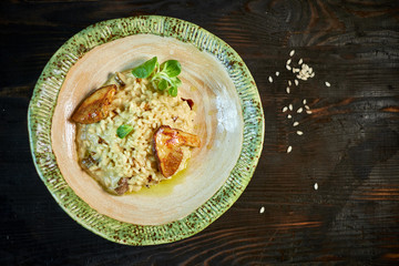Risotto with chicken, peas and tomatoes on a wooden board, Italian