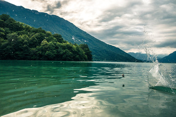 Stone skipping on mountain lake water