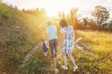 Fototapeta premium mother and father holding daughter hands and walking by mountains