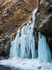 Fototapeta na wymiar Little frozen water fall in rock cliff and snow on the ground
