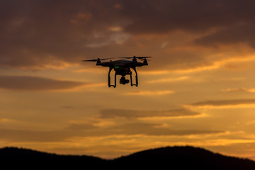Drone silhouette flying in sunset landscape