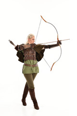 full length portrait of a blonde girl wearing green and brown medieval costume, holding a bow and arrow. isolated on white background.