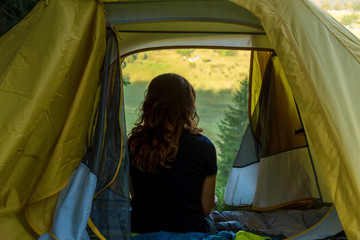 Young Woman rest in a tent with a view of the mountain landscape