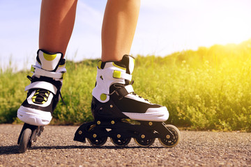 Female legs in inline skates in action outdoors on sunny day. Fun time activity.