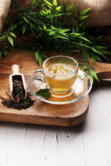 Cup with green tea on brown wooden background with mint leaves