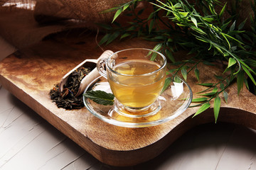 Cup with green tea on brown wooden background with mint leaves