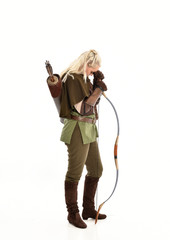 full length portrait of a blonde girl wearing green and brown medieval costume, holding a bow and...