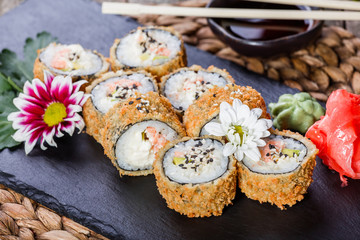 Hot fried Sushi rolls and maki set with Crab Meat, cream cheese, avocado and wasabi on black stone on bamboo mat, selective focus. Japanese cuisine