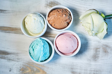 Selection of gourmet flavours of Italian ice cream in vibrant colors served in individual porcelain cups on an old rustic wooden table in an ice cream parlor, angle view jpg
