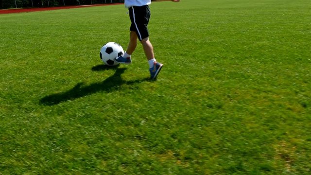 Tracking camera of a little 3 years old boy scoring a goal in a football field
