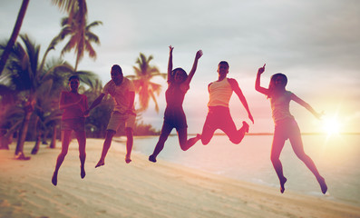 happy friends dancing and jumping on beach