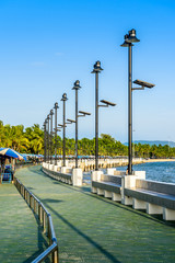 Walkway at seaside with sunlight and blue sky.