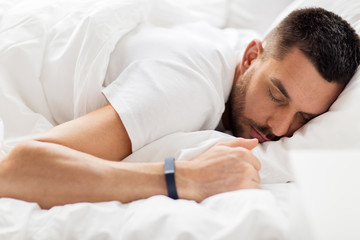 man with smartwatch sleeping in bed