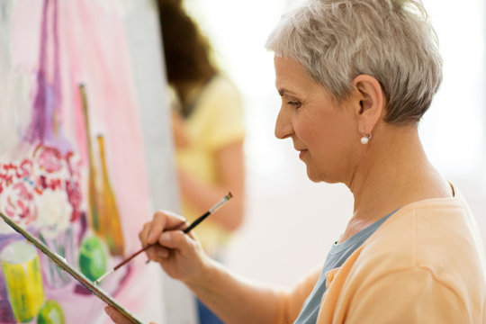 senior woman artist painting at art school