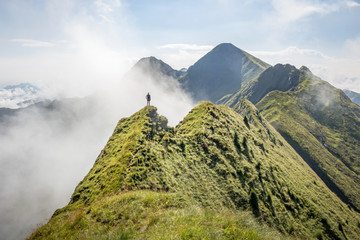 Female hiker standing on a mountain ridge with clouds