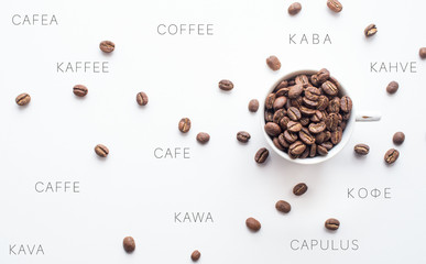 Bright coffee beans in a cup and spread over a light background with coffee spelled in different languages, representing an international component to coffee consumption. 