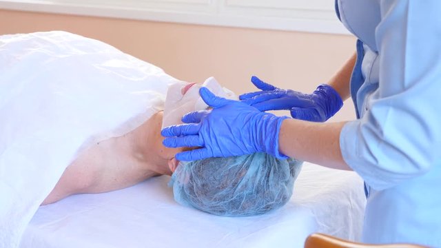 Spa therapy for elderly woman receiving facial mask. 4k. Slow motion. Reception of a cosmetologist