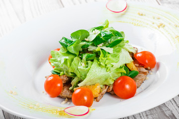 Fresh salad with chicken breast, baby spinach, lettuce, cherry tomatoes and cheese on wooden background close up