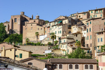 Fototapeta na wymiar Ancient houses on the slope of the mountain at old Siena on Italy