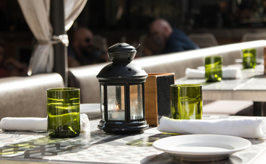 Summer day restaurant setting decor with white plates, green glasses and black lanterns