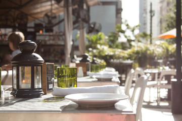 Summer day restaurant setting decor with white plates, green glasses and black lanterns