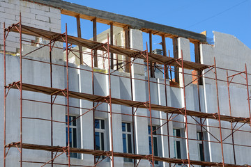 Formwork. Reconstruction,Construction of a building with external insulation. Building insulation and plaster, scaffolding. Modern building unfinished