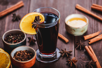 Christmas mulled wine with cinnamon, anise stars, honey and orange slices on wooden background with Holiday light