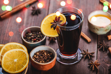 Christmas mulled wine with cinnamon, anise stars, honey and orange slices on wooden background with Holiday light