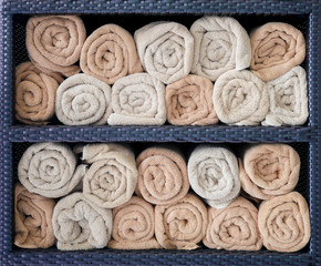 Hotel towels rolled in shelf.