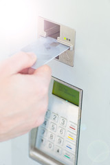 Close-up of person's hand inserting credit card into machine to pay ticket
