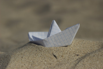 White paper boat on the sand