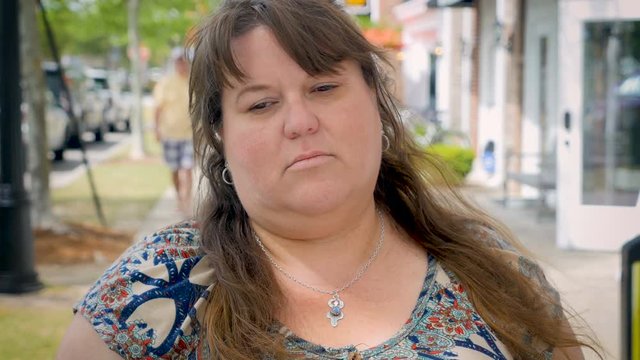 A depressed young overweight woman standing outside on the street